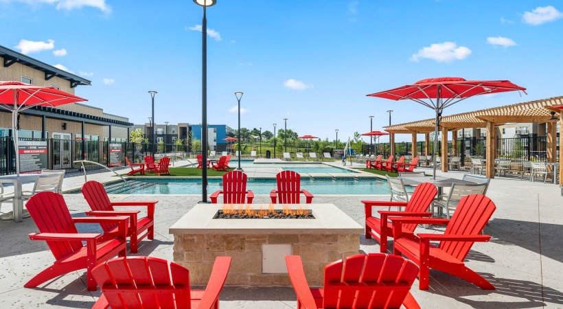 a group of red chairs around a fire pit by a pool